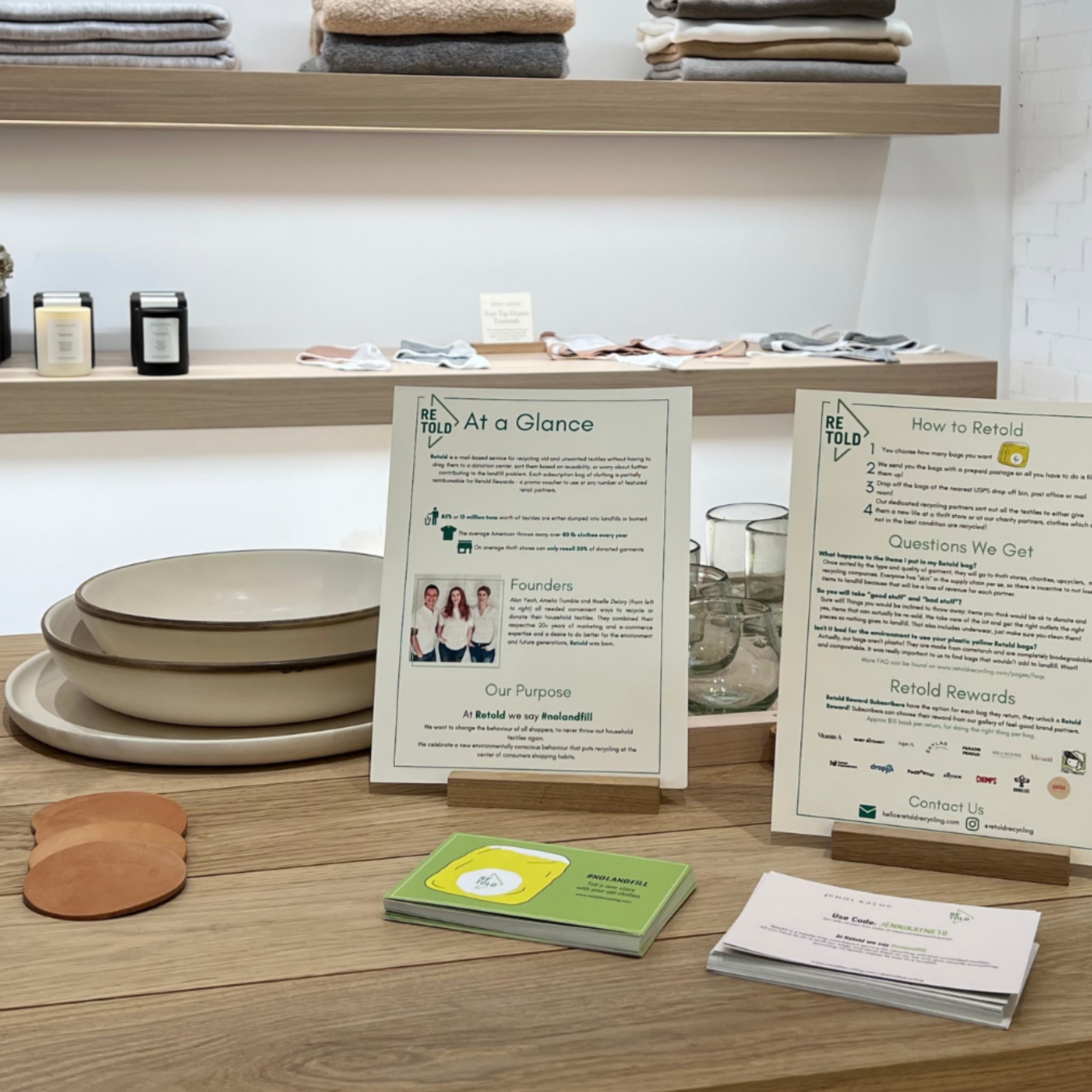 Display of plates, coasters, and informational brochures on a wooden surface with shelves in the background.